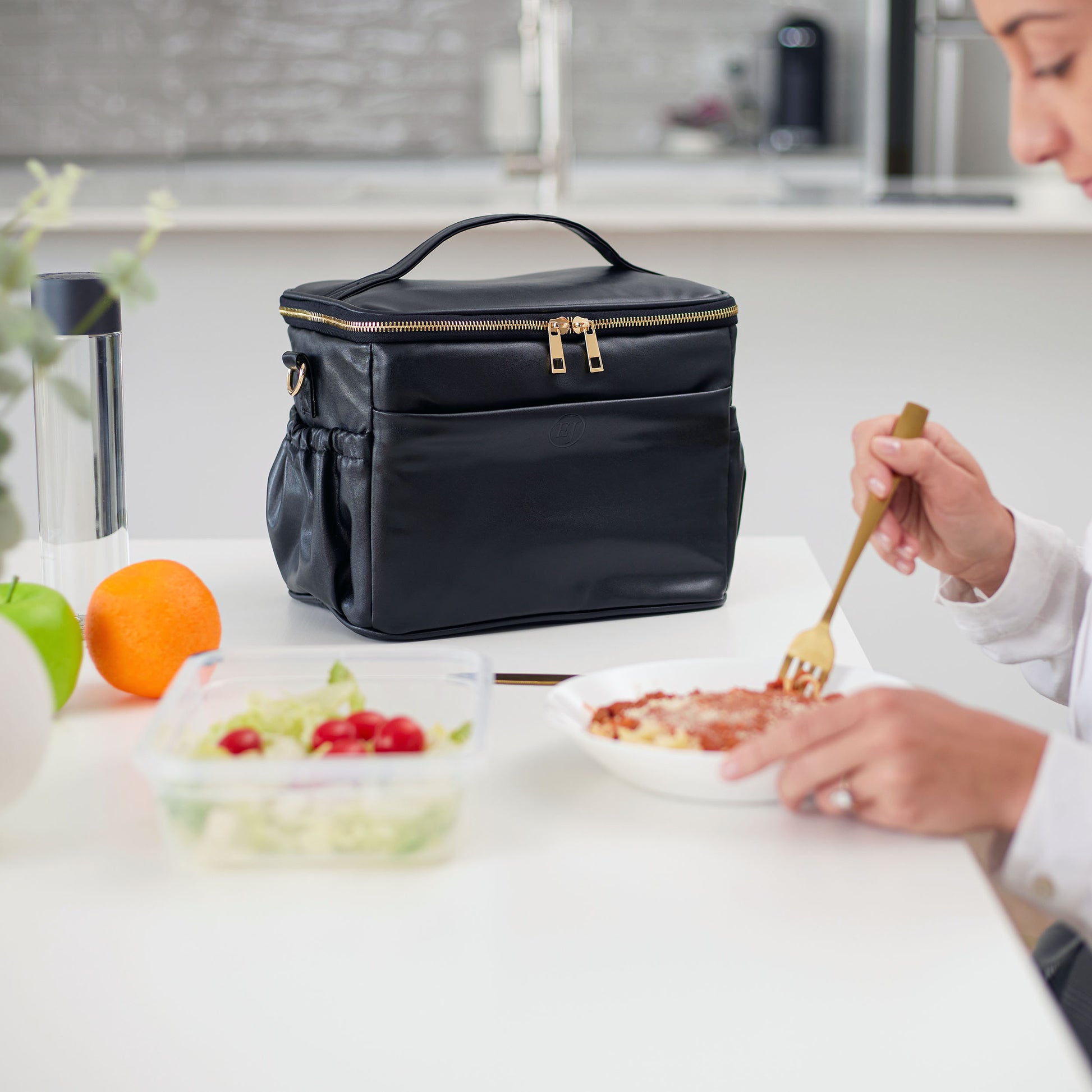 black leather lunch bag at the office kitchen with a model eating pasta bolognese